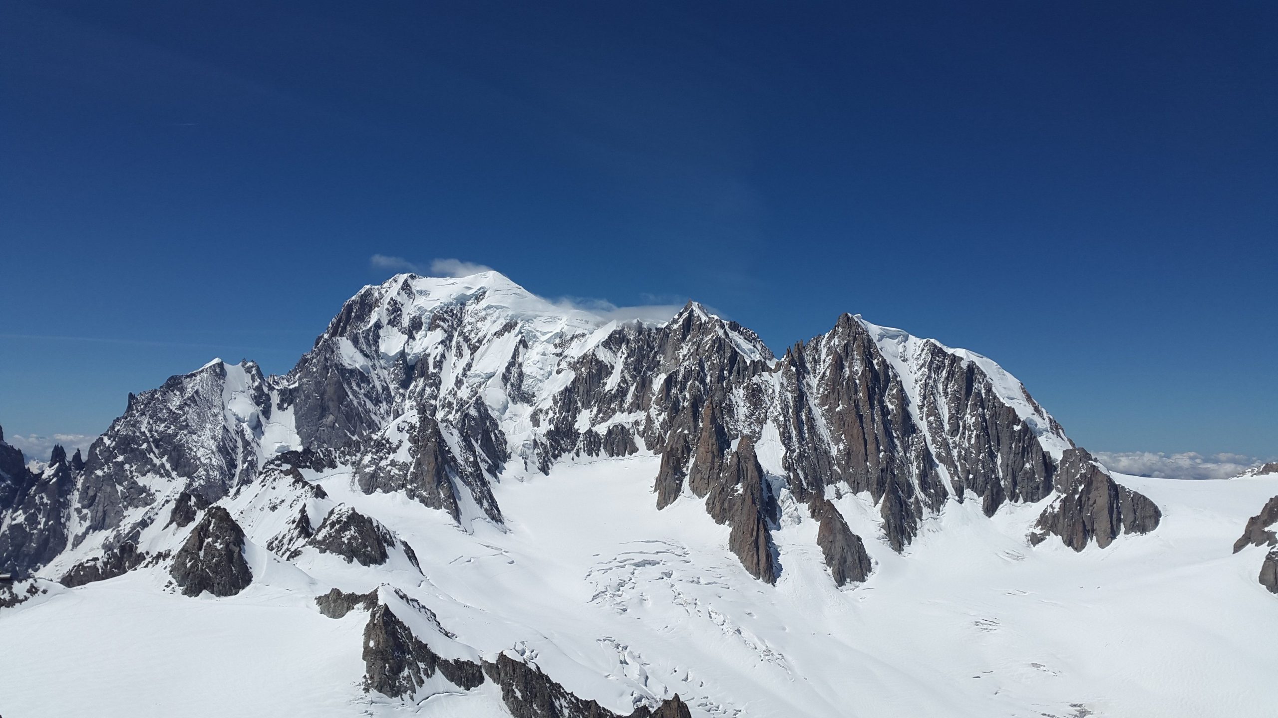 Snow topped mountain with a deep blue sky above. Alps like in appearance.